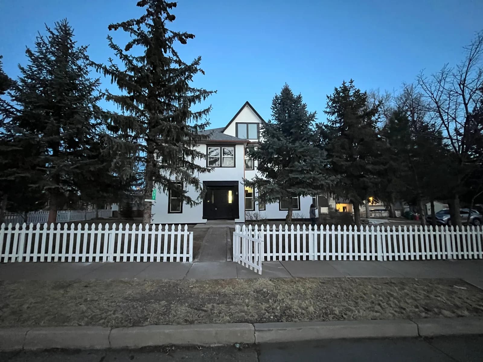 New white picket fence installed along the front of a two-storey home in Colorado Springs