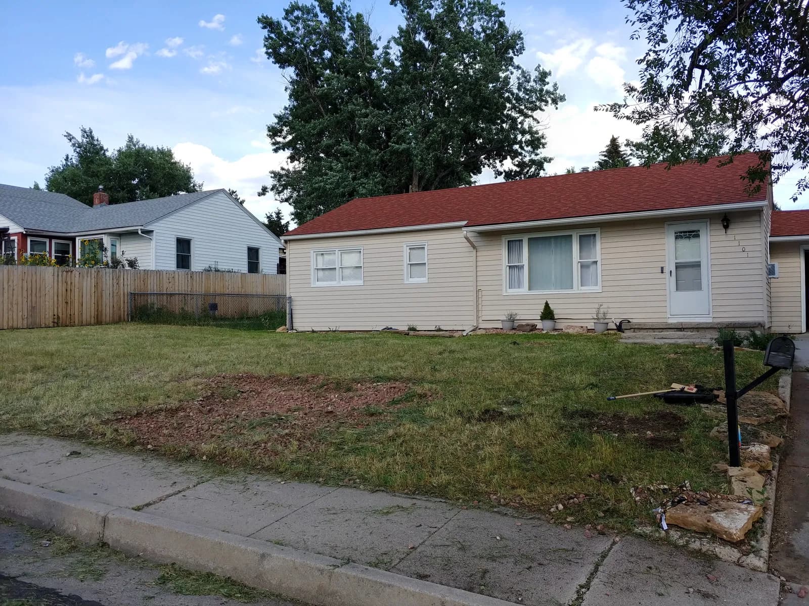 The same front yard after clean-up — weeds cleared, lawn mowed, and fresh beds cut in along the foundation