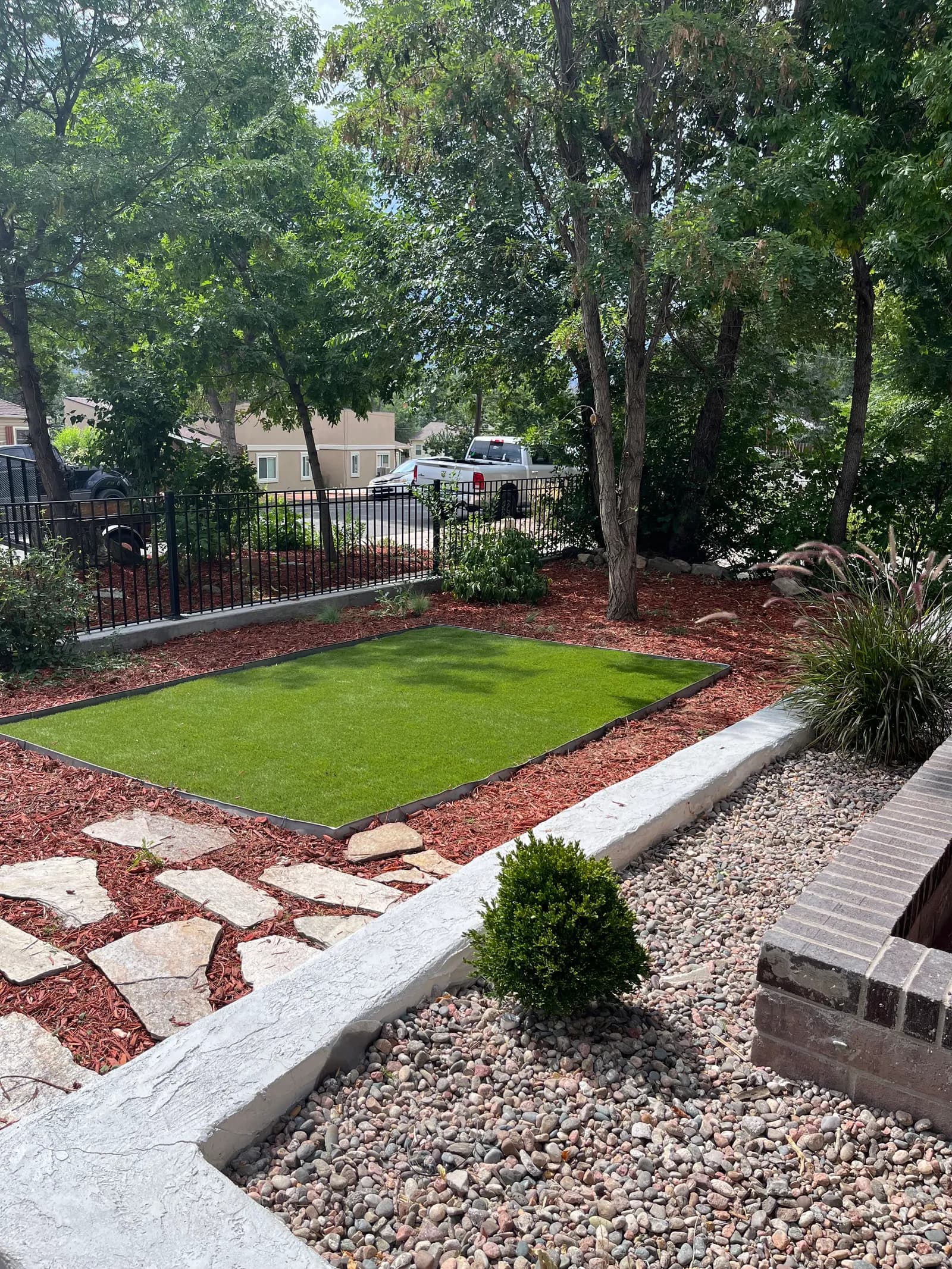 The finished turf lawn — an even green rectangle framed by red mulch, flagstone and river rock